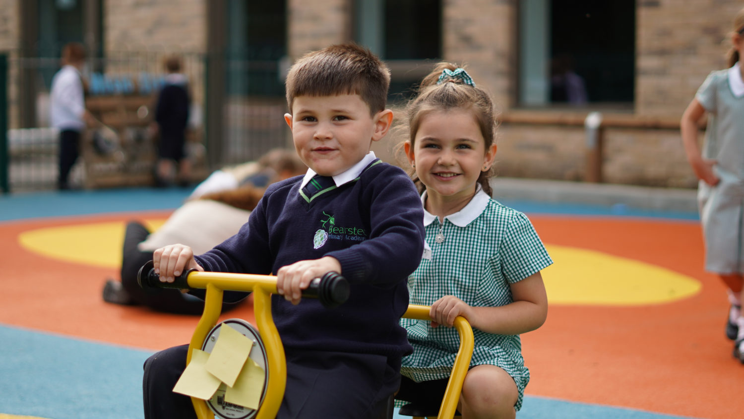 Two children pictured playing together on outdoor bikes.